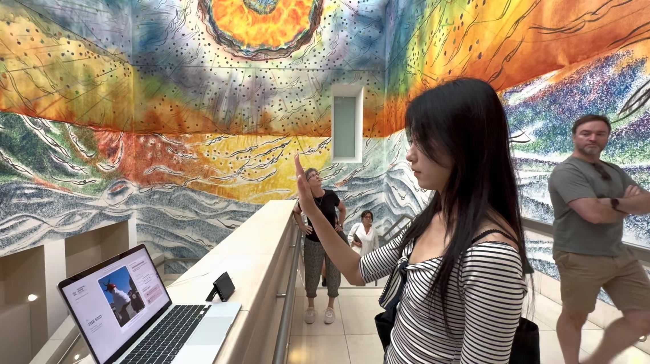 A visitor using a hand gesture beside the public computer in a colourful exhibition space
