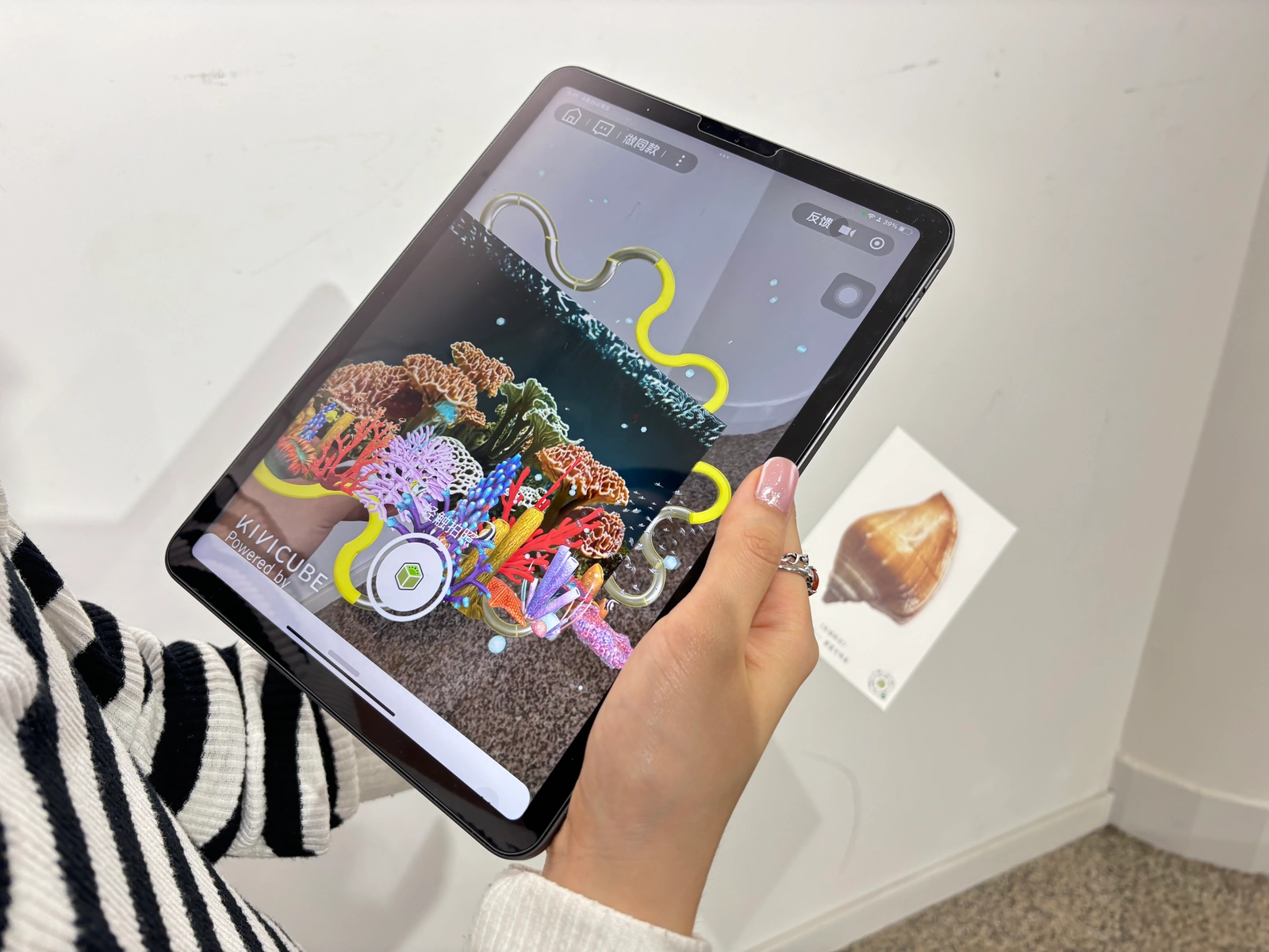 A tablet showing the first AR environment beside a physical postcard
