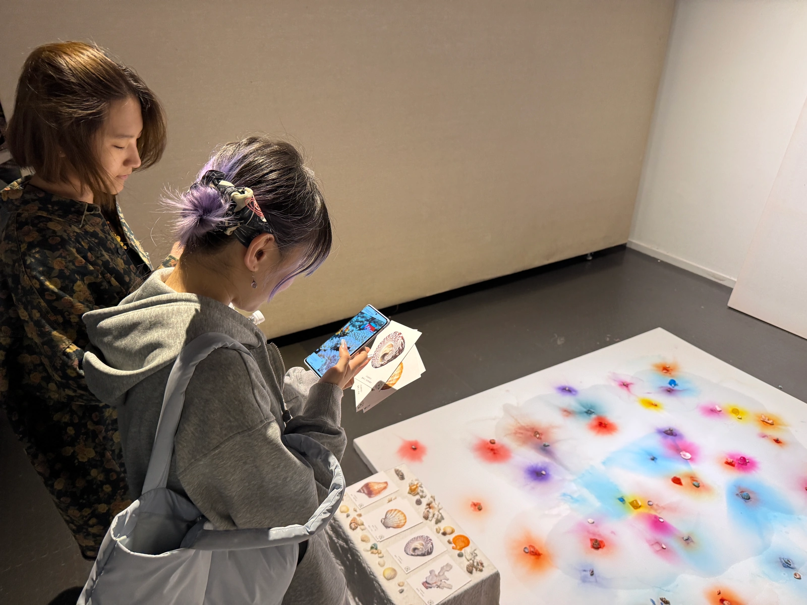 A visitor with postcards watching AR on a phone