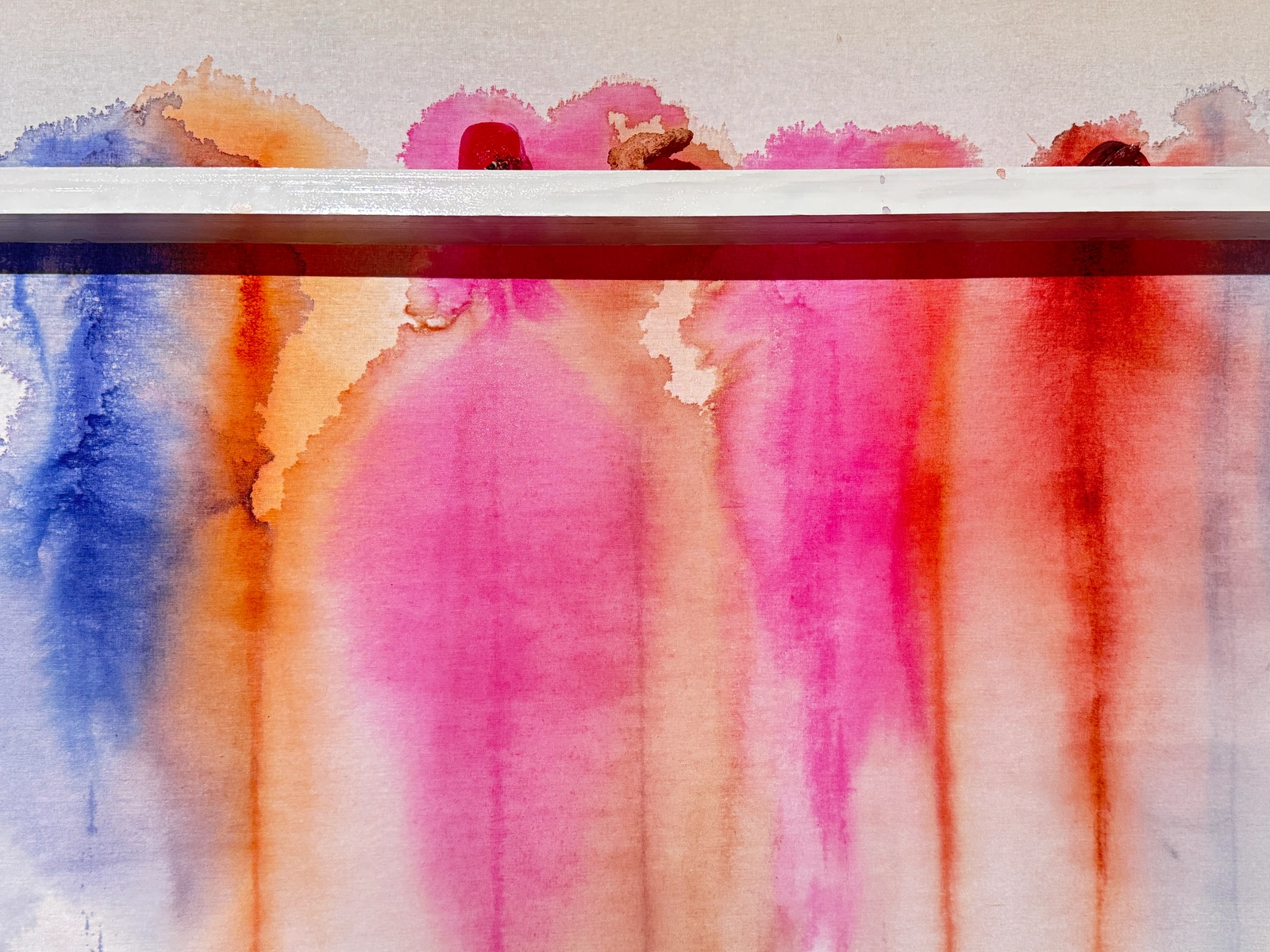 Blue, pink and orange pigment flowing down the hanging canvas